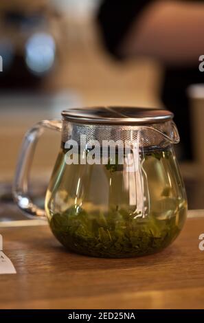 gros plan de la théière en verre avec thé vert sur la table dans le café avec arrière-plan flou, personne Banque D'Images