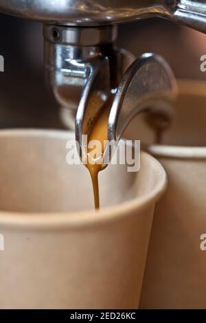 macro de café versé à partir d'une machine espresso professionnelle dans une tasse en papier à emporter, gros plan Banque D'Images
