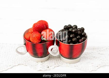 fraises et raisins de corinthe noirs dans une tasse, concept été dans le village Banque D'Images