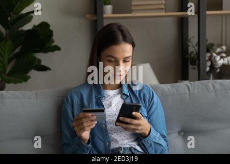 Une jeune femme ciblée vérifie le solde du compte carte sur l'application téléphone Banque D'Images
