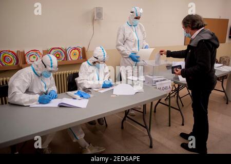 14 février 2021, Barcelone, Catalogne, Espagne: Un homme vote dans un bureau de vote de Barcelone avec des travailleurs portant des combinaisons PPE lors des élections régionales catalanes tenues dans le cadre de mesures strictes de sécurité sanitaire en raison d'une pandémie de coronavirus.Credit: Jordi Boixareu/Alay Live News Banque D'Images