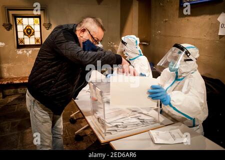 14 février 2021, Barcelone, Catalogne, Espagne: Un homme vote dans un bureau de vote de Barcelone avec des travailleurs portant des combinaisons PPE lors des élections régionales catalanes tenues dans le cadre de mesures strictes de sécurité sanitaire en raison d'une pandémie de coronavirus.Credit: Jordi Boixareu/Alay Live News Banque D'Images