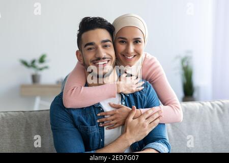 Portrait d'un couple musulman joyeux qui s'embrasse chez lui Banque D'Images