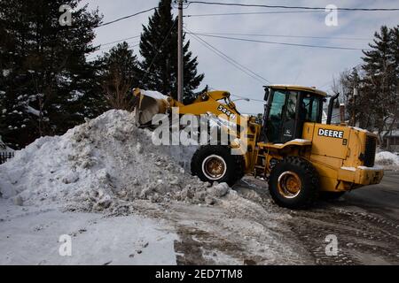 Une chargeuse sur pneus John Deere 544H déplace des masses de neige sur le côté d'une autoroute dans un distributeur, NY USA Banque D'Images