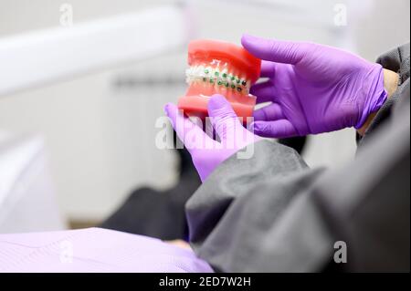 Dentiste montrant au patient un modèle dentaire d'orthodontie, expliquant au patient le traitement d'orthodontie en clinique dentaire. Photo de haute qualité Banque D'Images