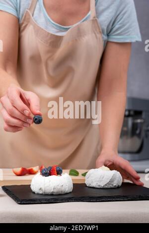 Confiseur décorant meringue avec des baies fraîches. Processus de fabrication des gâteaux Banque D'Images