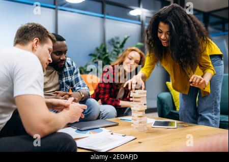 Un groupe multiethnique de jeunes gens d'affaires siègent dans un bureau moderne. Des collègues ou des étudiants souriants et amicaux font une pause de travail ou d'étude, se reposent sur le brainstorming et jouent ensemble Banque D'Images