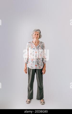 Femme âgée dans ses années 80 avec des cheveux gris debout isolés sur fond blanc Banque D'Images