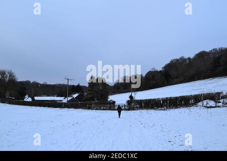 Un seul marcheur sur un sentier à Magpie Bottom, Kent, près d'Otford, Darent Valley, en février neige. Conditions difficiles, sombre, froid, sinistre, sinistre, effrayant Banque D'Images