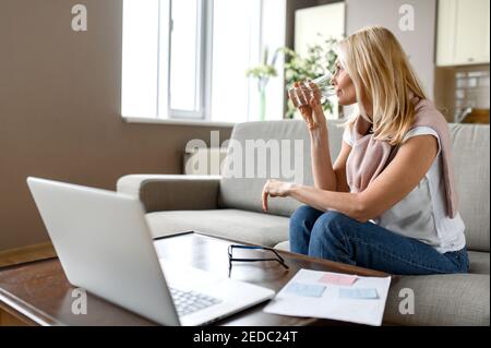 Une femme adulte suit un mode de vie sain. Occupée femme d'affaires réussie prenant une pause de travail à distance ou d'apprentissage, de boire de l'eau tout en travaillant ou d'étudier le processus Banque D'Images