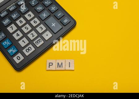 Expression ou mot - pmi. Bloc de lettres en bois et calculatrice moderne sur fond jaune, concept d'affaires avec espace pour le texte Banque D'Images