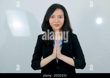 La jeune fille asiatique d'affaires donne la main de salutation avec un grand sourire sur son visage. Femme indonésienne sur fond gris. Banque D'Images