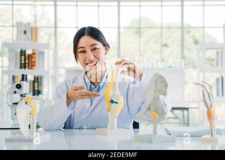 Portrait d'une jeune femme asiatique médecin portant un blouse de travail préparant un modèle osseux tout en expliquant l'anatomie à l'hôpital pour une vidéo blog Banque D'Images