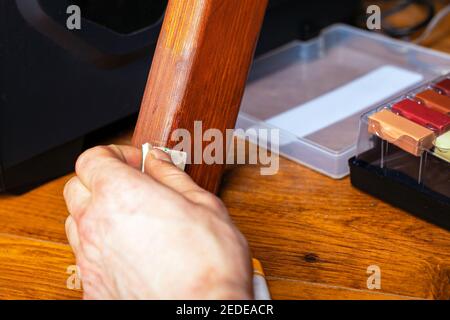 master essuie une rayure sur une jambe de meubles en bois réparation de restauration Banque D'Images