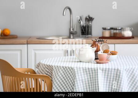 Théière, tasses et muffins sur table dans la cuisine Banque D'Images