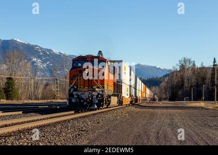 Une locomotive de poussée tractée, 6773 ans, d'un train de fret à conteneurs intermodal BNSF descendant les voies dans la ville de Troy, Montana. Banque D'Images