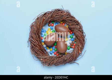 Nicher avec des œufs au chocolat doux et des bonbons sur fond de couleur Banque D'Images