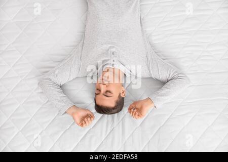 Matin d'un jeune homme allongé sur un matelas souple, vue du dessus Banque D'Images