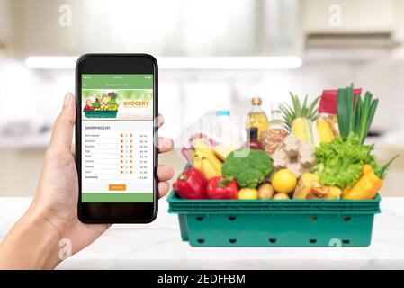 Application d'achat en ligne d'épicerie sur l'écran du téléphone intelligent avec la nourriture à accueil en arrière-plan Banque D'Images