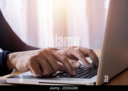 Gros plan homme d'affaires utilisant un ordinateur portable à la maison. Gros plan des mains de sexe masculin en tapant sur le clavier d'un ordinateur portable au bureau. Homme mains utilisant le clavier d'ordinateur portable. Gros plan Banque D'Images