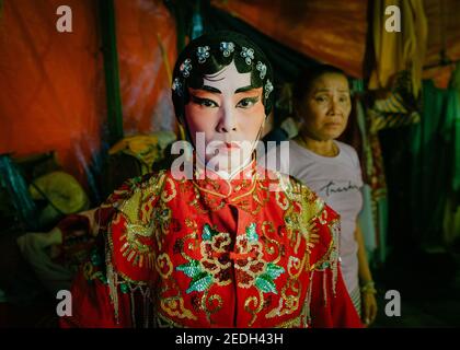 Portrait d'un opéra chinois thaïlandais en coulisses, portant son costume et son maquillage colorés, son commode est en arrière-plan. Banque D'Images