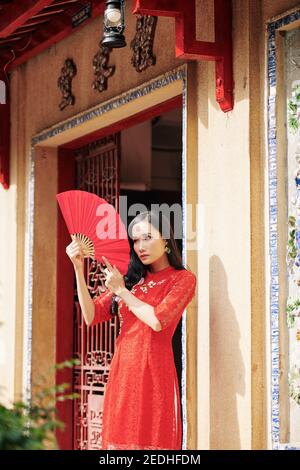 Femme asiatique posant avec un fan de papier Banque D'Images