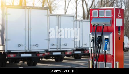Poste de charge de véhicules électriques sur fond d'une rangée de camions. Concept Banque D'Images