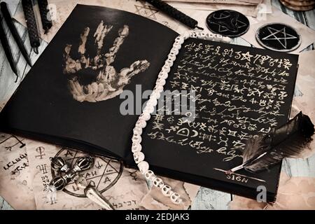 Encore la vie avec le livre de la grimoire du sort magique, bougies noires sur table de sorcière, vendre l'âme au concept du diable. Arrière-plan ésotérique, gothique et occulte, non Banque D'Images