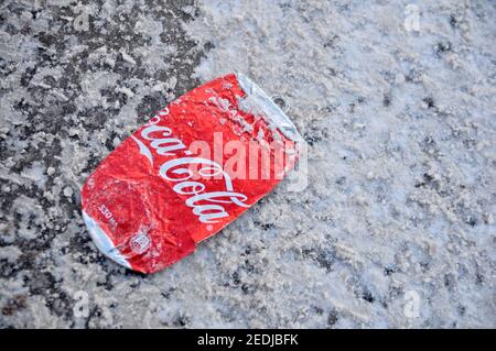 Coca-Cola peut aplatir sous les roues de voitures sur une route d'hiver. Banque D'Images