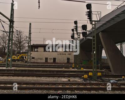 Voies de chemin de fer, pont et ancien bâtiment à la gare centrale de Lindau par temps nuageux d'hiver. Ciel de couleur orange en raison du phénomène météorologique (poussière de Sahara). Banque D'Images