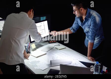 L'équipe d'architectes asiatiques qui reste tard dans la nuit dans les discussions au bureau projet de conception du plan d'étage à la table de réunion Banque D'Images