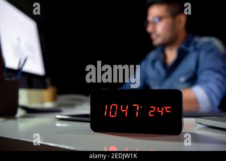 Homme de travail qui reste des heures supplémentaires tard la nuit dans le bureau travailler avec un ordinateur à son bureau Banque D'Images