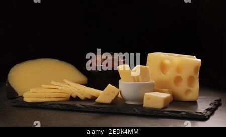 différents types de fromage coupés en tranches se trouvent sur la pierre assiette avec miel et noyer sur fond sombre Banque D'Images