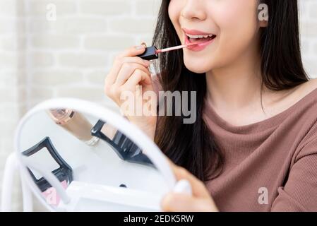 Jeune belle femme professionnelle de beauté vlogger ou blogger appliquant la crème rouge à lèvres à sa bouche, faisant maquillage cosmétique tutoriel Banque D'Images