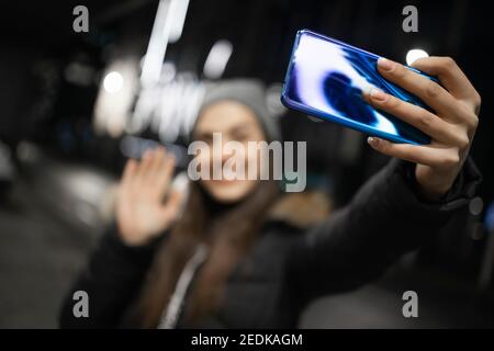 Une belle fille qui agite à un appareil photo de smartphone Banque D'Images