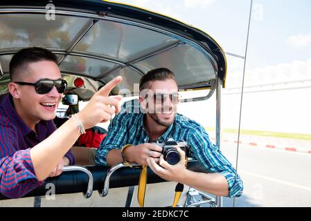 Deux amis touristes sont excités et s'amusent Taxi Tuk Tuk local en voyageant dans la ville de Bangkok en Thaïlande Banque D'Images