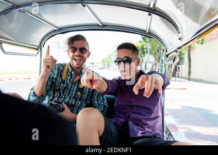 Deux amis touristes sont enthousiastes et s'amusent sur le taxi Tuk Tuk local lors de leur voyage à Bangkok, en Thaïlande Banque D'Images