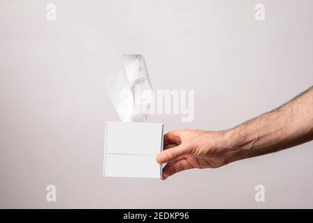 Main mâle tenant une boîte de tissus cubiques sur fond blanc, modèle de série maquette modifiable prêt pour votre conception, chemin de sélection des visages inclus. Banque D'Images