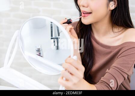 Jeune belle femme professionnelle de beauté vlogger ou blogger appliquant la crème rouge à lèvres à sa bouche, faisant maquillage cosmétique tutoriel Banque D'Images