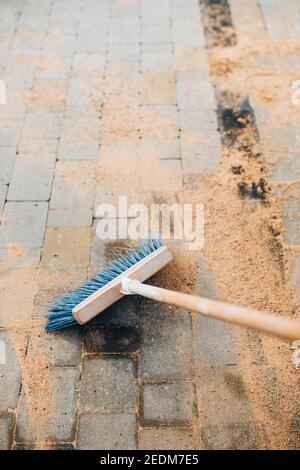 Sable fin ensemencé sur les dalles de pavage - coulis avec un brosse Banque D'Images