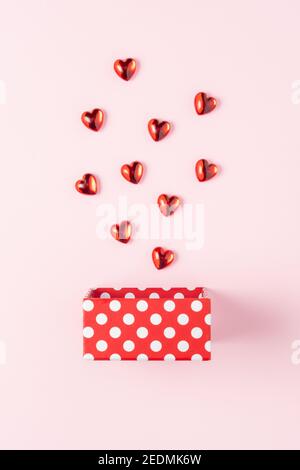 Boîte cadeau avec coeurs sur fond rose. Concept d'amour minimal. Banque D'Images