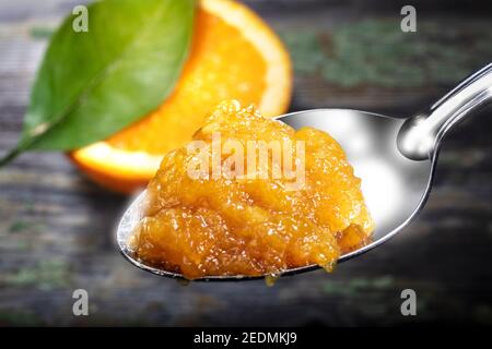 Focus sélectif sur le Spoon de la marmelade orange. Le fond en bois est décoré avec une tranche et une laisse d'orange. Banque D'Images