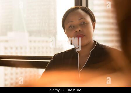 Puissante femme d'affaires noire qui regarde et écoute son collègue en réunion de bureau Banque D'Images