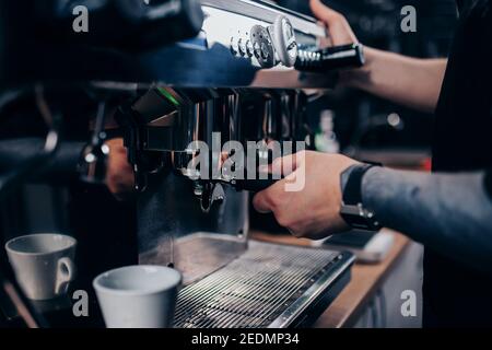 Le barista se donne les mains au travail - une machine à café professionnelle dans un cafe - préparation d'espresso Banque D'Images