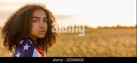 Panorama triste déprimé mixte race afro-américaine fille adolescente femme jeune femme dans un champ de blé ou d'orge Enveloppé d'étoiles et de bandes aux États-Unis Banque D'Images