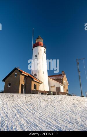 Hiver à Urk avec la digue et la plage au phare d'Urk neige couverte pendant l'hiver, coucher de soleil au phare d'Urk Flevoland. Pays-Bas Banque D'Images