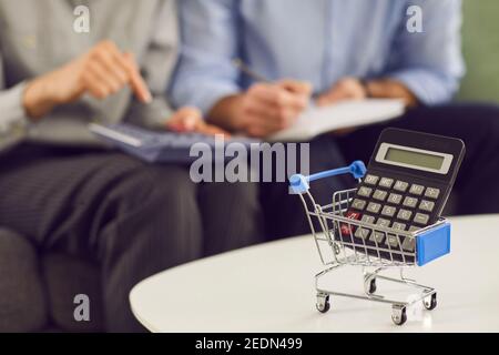 Gros plan du chariot de magasinage et de la calculatrice avec les gens qui calculent les dépenses en arrière-plan Banque D'Images
