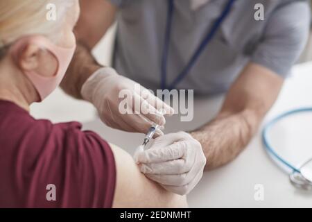 Gros plan d'un médecin méconnaissable qui vaccine une femme âgée portant un masque contre le covid 19, espace de copie Banque D'Images