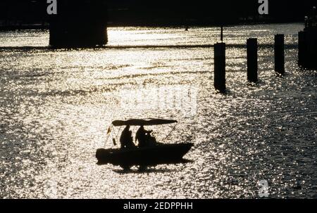 12 février 2021, Hessen, Francfort-sur-le-main : deux hommes naviguent dans un petit bateau au coucher du soleil sur le main. Photo: Andreas Arnold/dpa Banque D'Images