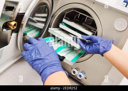 mains du médecin dans des gants en caoutchouc retirer les instruments stériles d'un autoclave. Banque D'Images